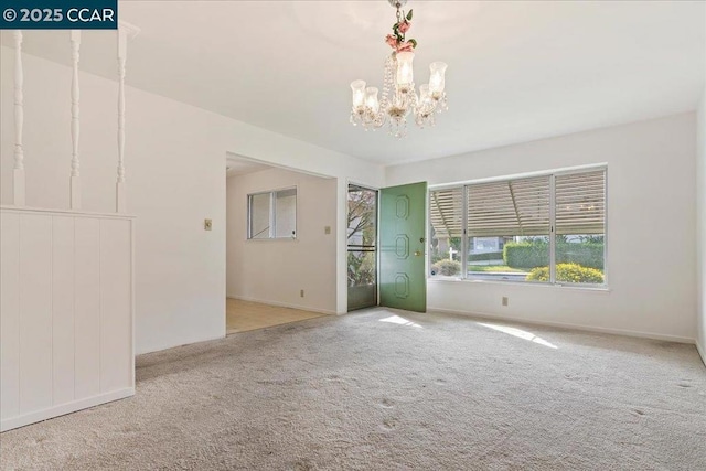 spare room with light colored carpet and a notable chandelier