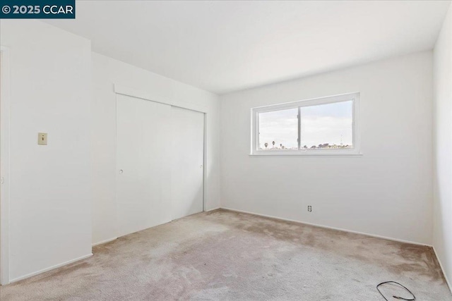 unfurnished bedroom featuring light carpet and a closet