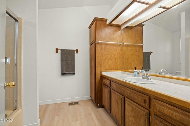 bathroom with vanity, combined bath / shower with glass door, and hardwood / wood-style floors