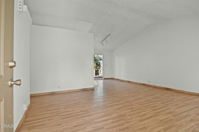 unfurnished living room with track lighting, a textured ceiling, and light hardwood / wood-style floors