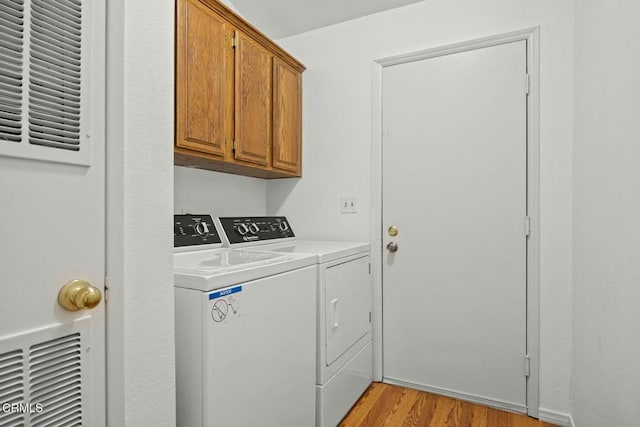 laundry room featuring cabinets, light hardwood / wood-style floors, and washing machine and dryer