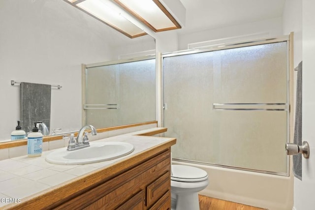 full bathroom with enclosed tub / shower combo, wood-type flooring, vanity, and toilet