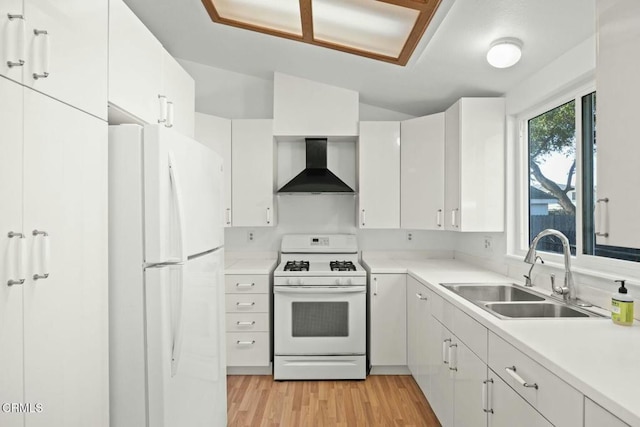 kitchen with wall chimney range hood, white appliances, light hardwood / wood-style flooring, sink, and white cabinets