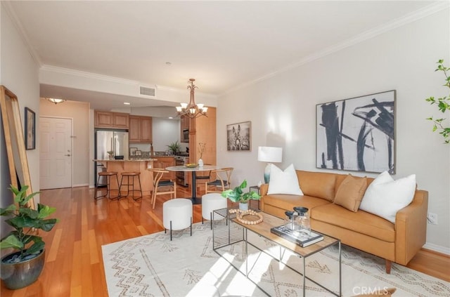 living room with a notable chandelier, light hardwood / wood-style flooring, and ornamental molding