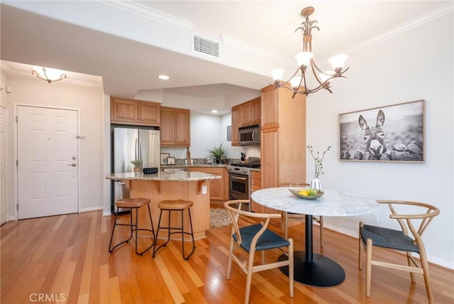 kitchen featuring crown molding, stainless steel appliances, a center island, and hanging light fixtures