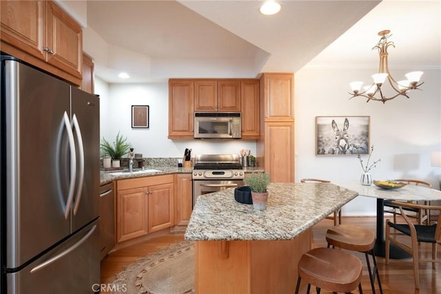 kitchen featuring appliances with stainless steel finishes, decorative light fixtures, sink, a center island, and light stone countertops