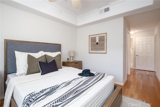 bedroom featuring hardwood / wood-style floors, ornamental molding, and ceiling fan