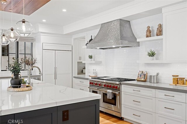 kitchen with premium range hood, white cabinets, premium appliances, and decorative light fixtures