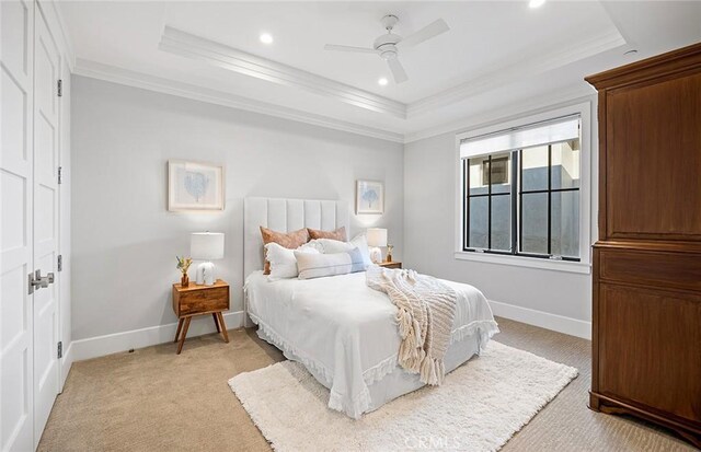 bedroom featuring crown molding, light colored carpet, and a tray ceiling