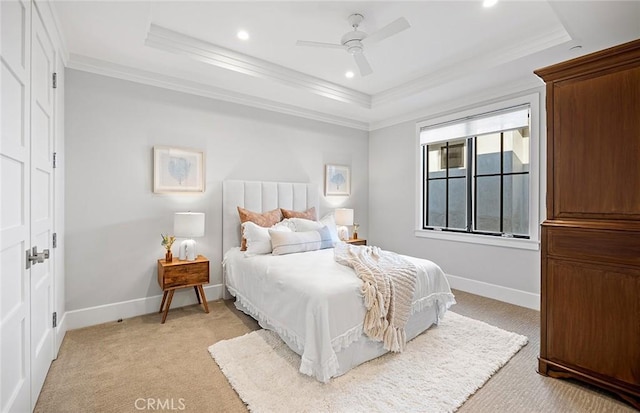 bedroom featuring light carpet, a tray ceiling, and baseboards