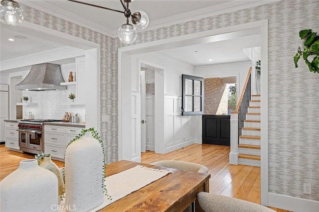 dining space with wallpapered walls, stairway, light wood finished floors, and crown molding