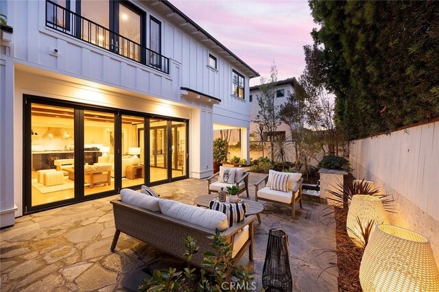 patio terrace at dusk with a balcony and an outdoor living space