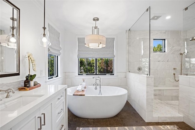 bathroom with a freestanding bath, walk in shower, vanity, and tile walls