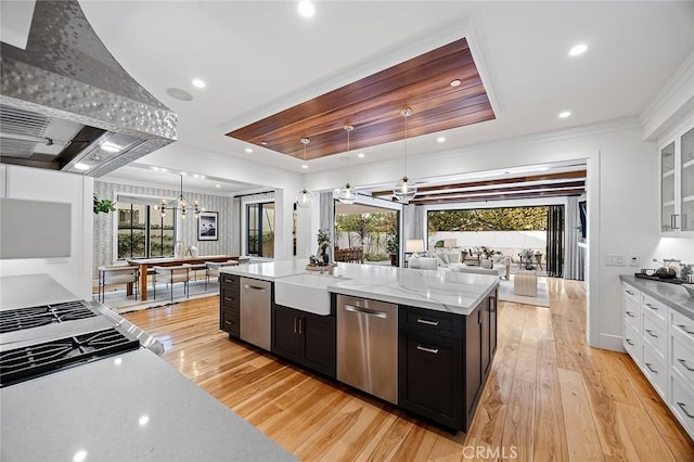 kitchen with sink, premium range hood, white cabinetry, hanging light fixtures, and stainless steel dishwasher