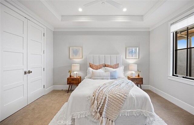 carpeted bedroom with ornamental molding and a tray ceiling