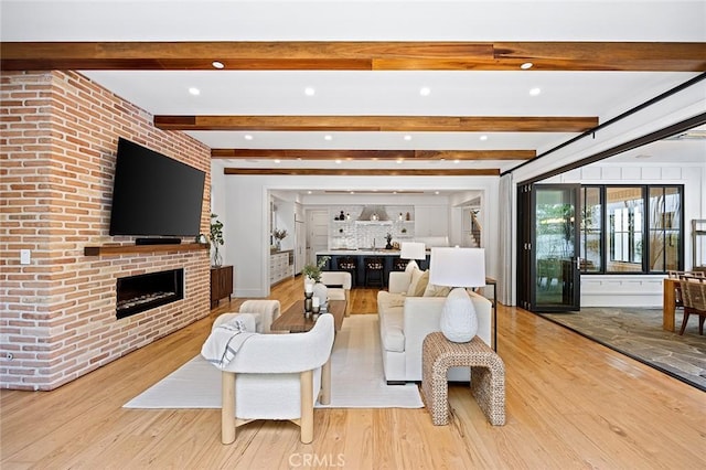 living room featuring a fireplace, beam ceiling, and light hardwood / wood-style floors