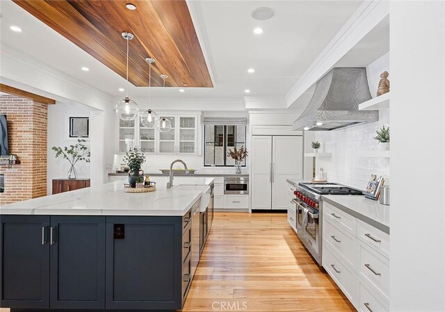 kitchen featuring white cabinets, hanging light fixtures, wall chimney exhaust hood, and high quality appliances