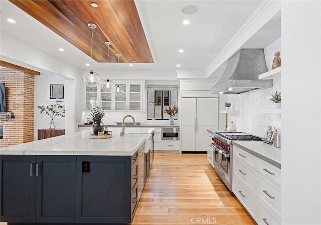 kitchen with premium appliances, open shelves, a spacious island, white cabinetry, and wall chimney range hood