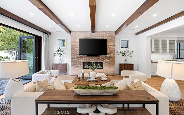 living room with beam ceiling, a fireplace, and light hardwood / wood-style floors