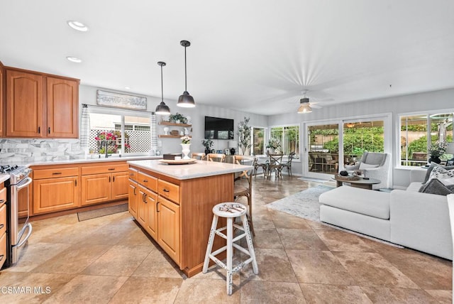 kitchen with a breakfast bar, pendant lighting, tasteful backsplash, a center island, and stainless steel range