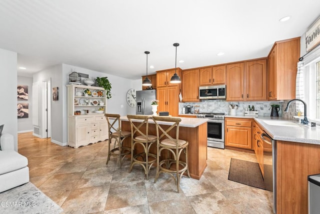 kitchen with a kitchen island, appliances with stainless steel finishes, sink, a breakfast bar area, and hanging light fixtures