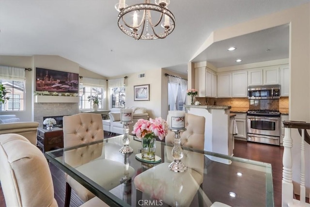 dining space featuring dark wood-type flooring, vaulted ceiling, and a notable chandelier