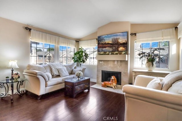 living room with lofted ceiling, a tiled fireplace, and dark hardwood / wood-style floors