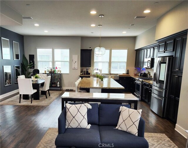 kitchen featuring stainless steel appliances, a kitchen island, hanging light fixtures, and plenty of natural light