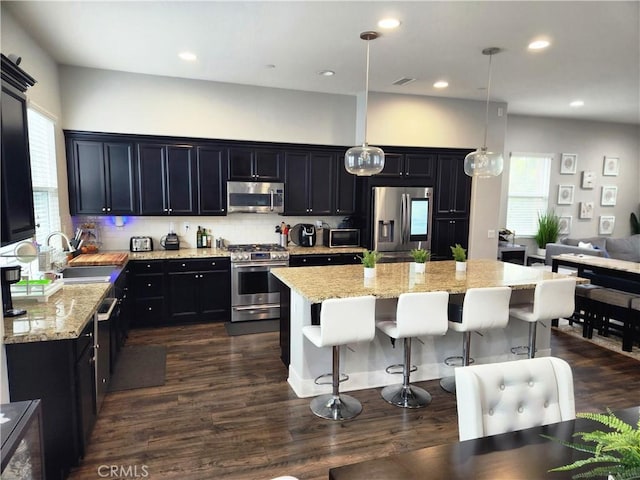 kitchen with hanging light fixtures, stainless steel appliances, sink, and a center island