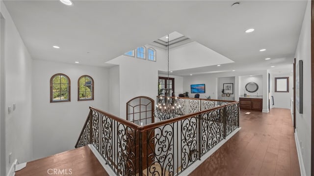 hallway featuring an inviting chandelier, wood-type flooring, and a healthy amount of sunlight