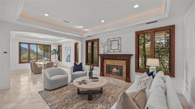 living room featuring a raised ceiling, crown molding, and a fireplace