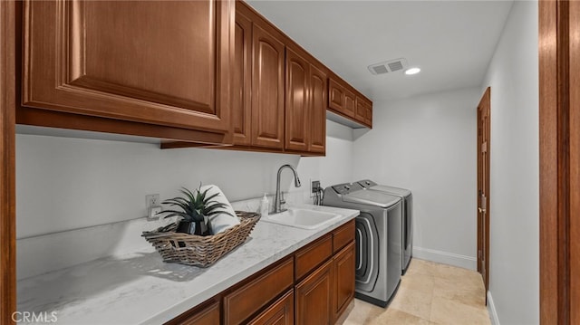 clothes washing area featuring sink, washer and clothes dryer, and cabinets