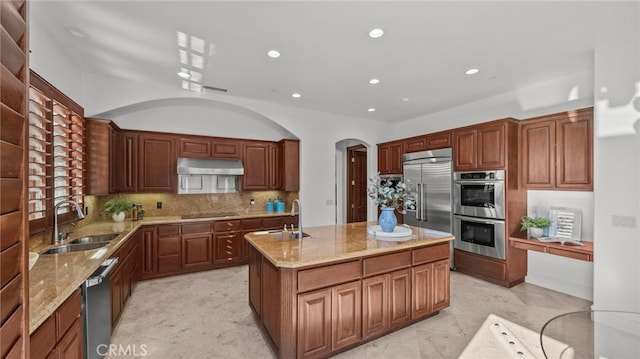 kitchen featuring stainless steel appliances, tasteful backsplash, sink, and a center island with sink