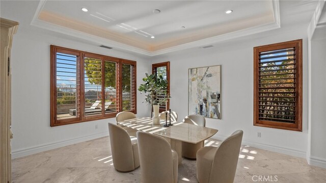 dining room with ornamental molding and a raised ceiling