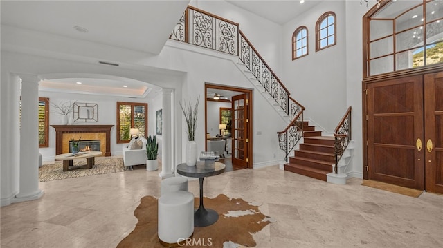 entryway featuring a towering ceiling, a fireplace, and decorative columns