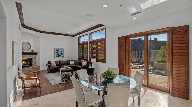 dining room with ornamental molding and a stone fireplace