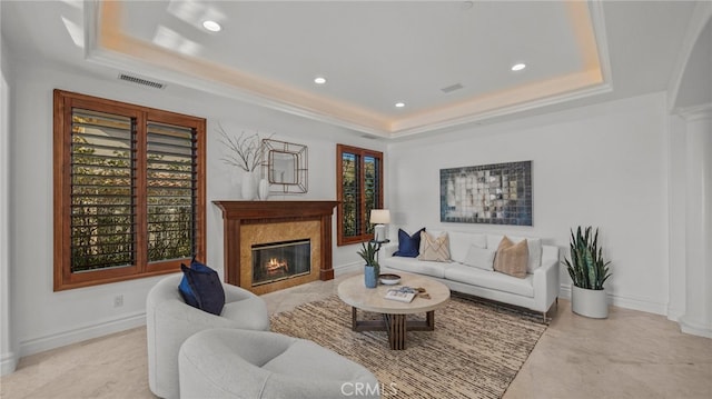 living room with a tray ceiling, a high end fireplace, and ornamental molding