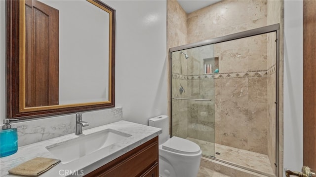 bathroom with a shower with door, vanity, and toilet