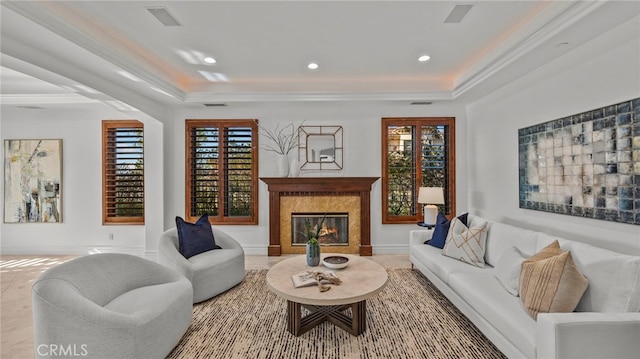 living room featuring a premium fireplace, crown molding, and a raised ceiling