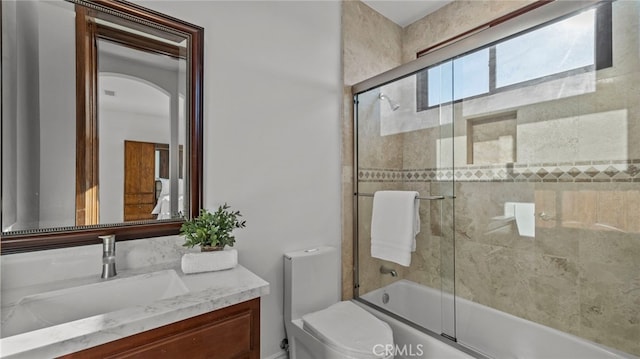 full bathroom featuring vanity, combined bath / shower with glass door, and toilet