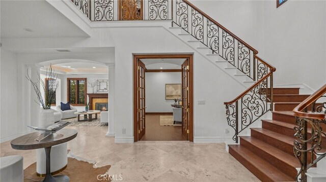 foyer entrance with ornamental molding and a towering ceiling