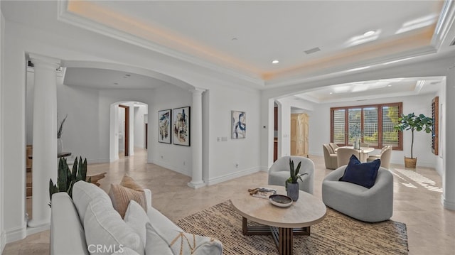 living room featuring a raised ceiling, ornamental molding, and ornate columns