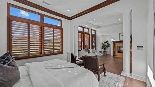 bedroom featuring crown molding, light hardwood / wood-style flooring, decorative columns, and a high end fireplace