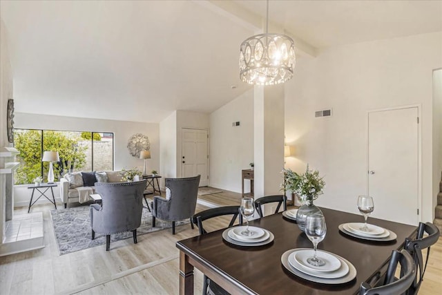 dining area featuring high vaulted ceiling, beam ceiling, light wood-type flooring, and a notable chandelier