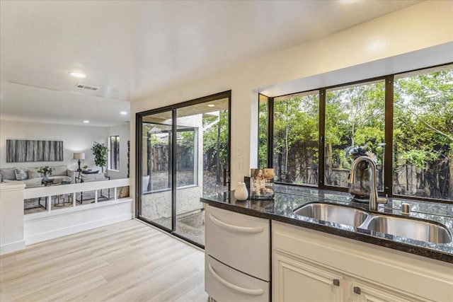 kitchen featuring sink, light hardwood / wood-style floors, dark stone counters, and dishwasher