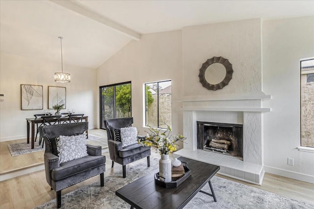 living room with wood-type flooring, beam ceiling, a high end fireplace, and a notable chandelier