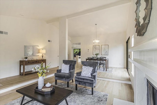 living room with a high end fireplace, high vaulted ceiling, light hardwood / wood-style floors, and a notable chandelier