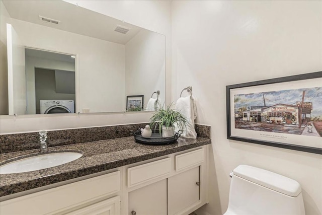 bathroom featuring vanity, washer / dryer, and toilet