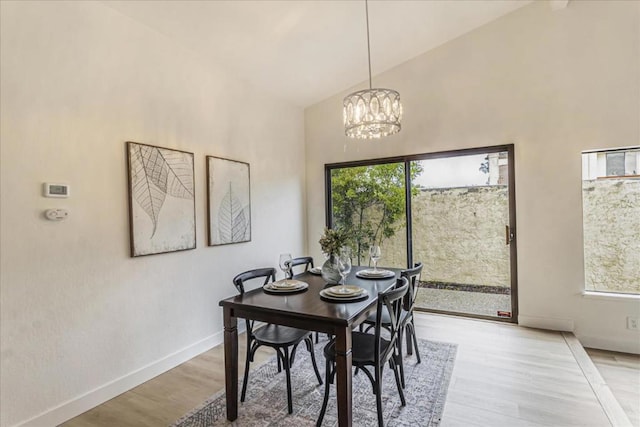 dining room featuring a notable chandelier, a wealth of natural light, light hardwood / wood-style floors, and high vaulted ceiling