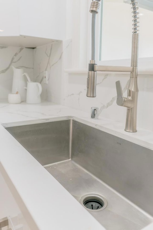 room details featuring light stone countertops, sink, and backsplash